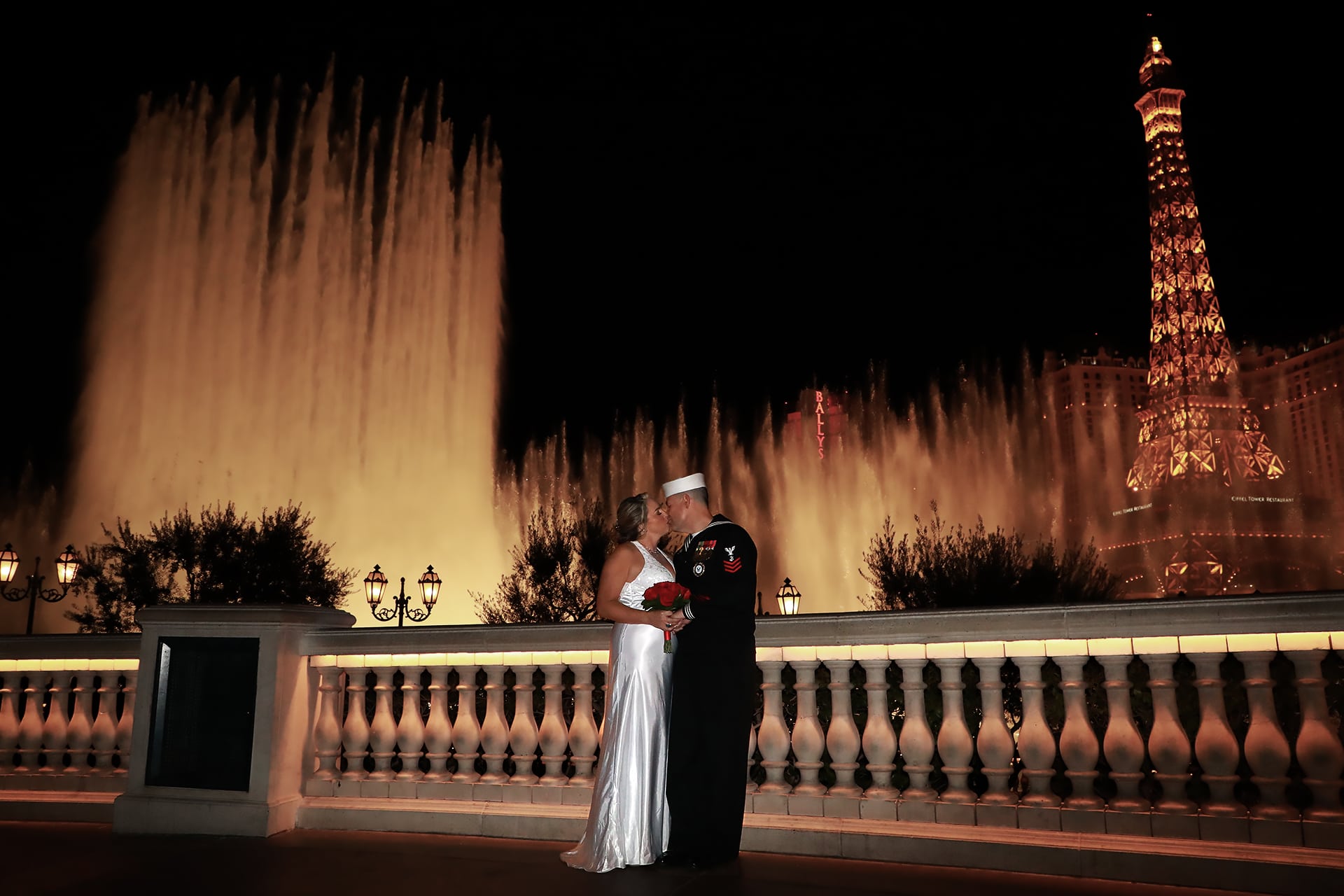 A bride and groom standing in front of a fountain in las vegas.
