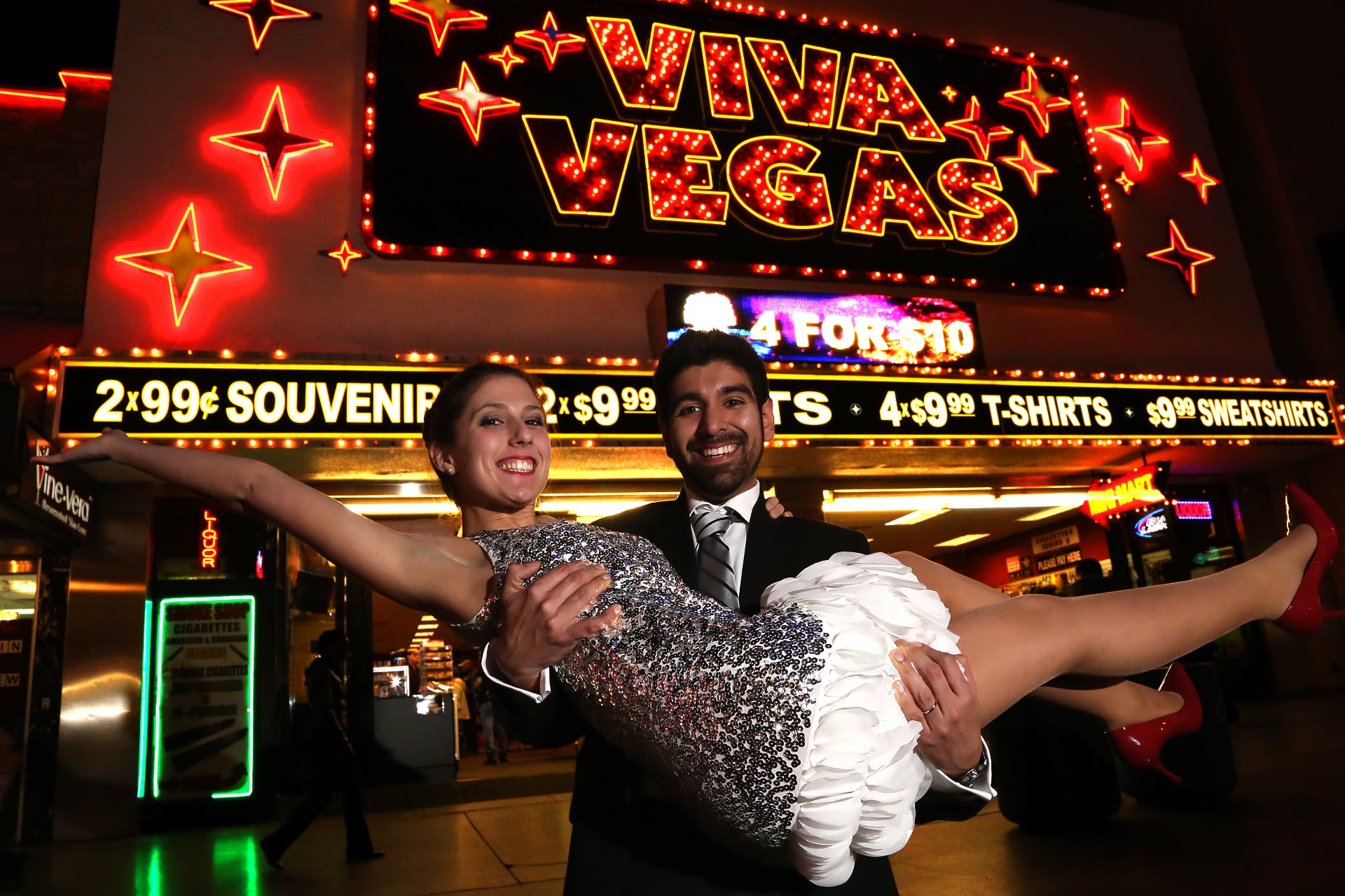 A couple in front of a viva vegas sign.