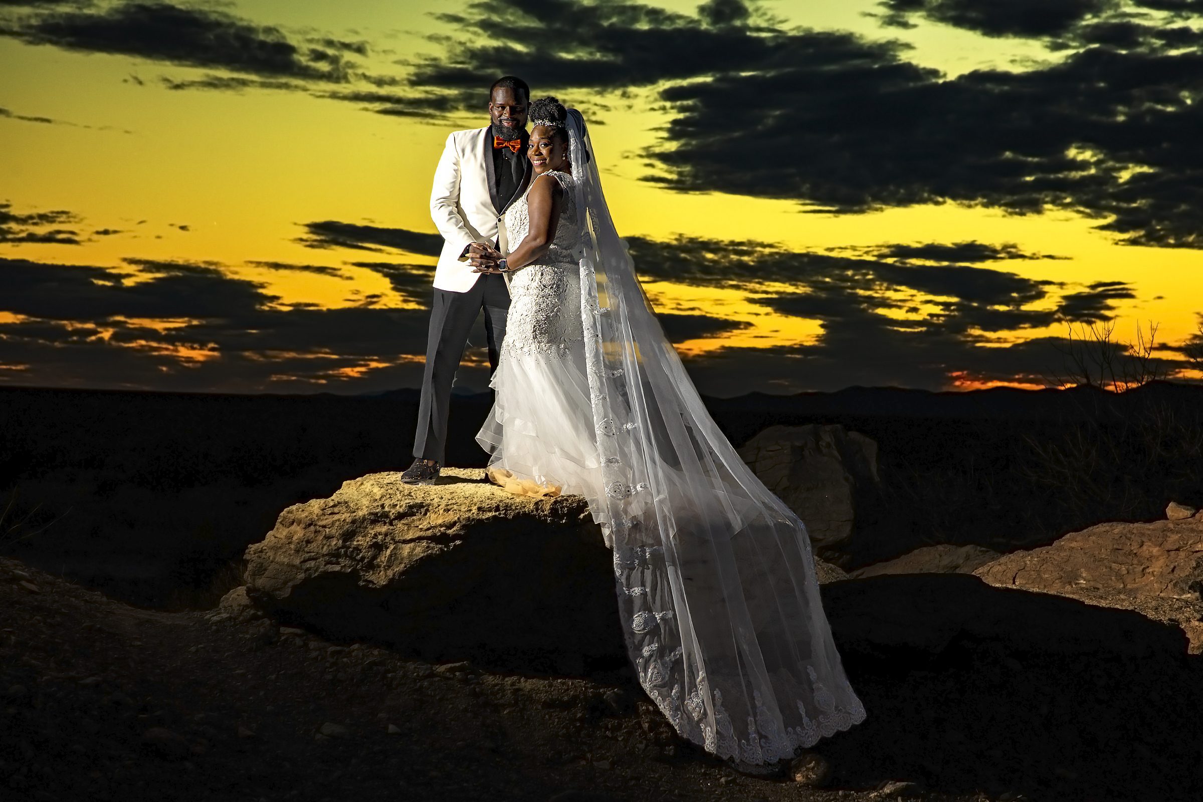 A bride and groom at Valley of Fire, capturing stunning wedding photos against a sunset backdrop on a rock.